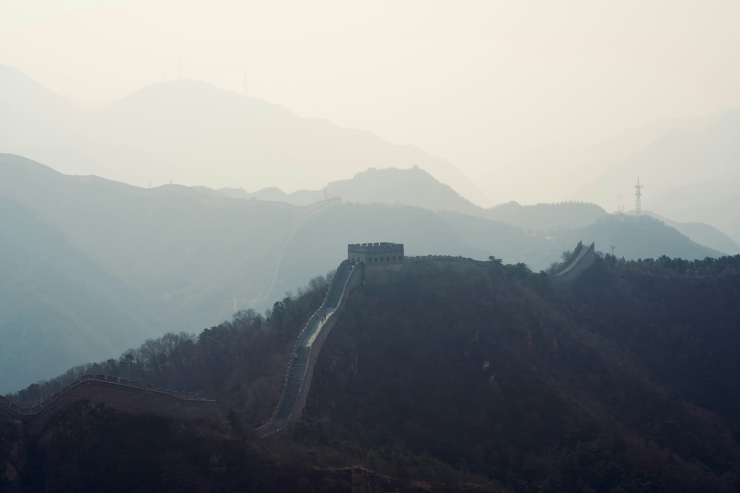 The Great Wall of China snaking along forested mountain ridges near Beijing under soft morning light
