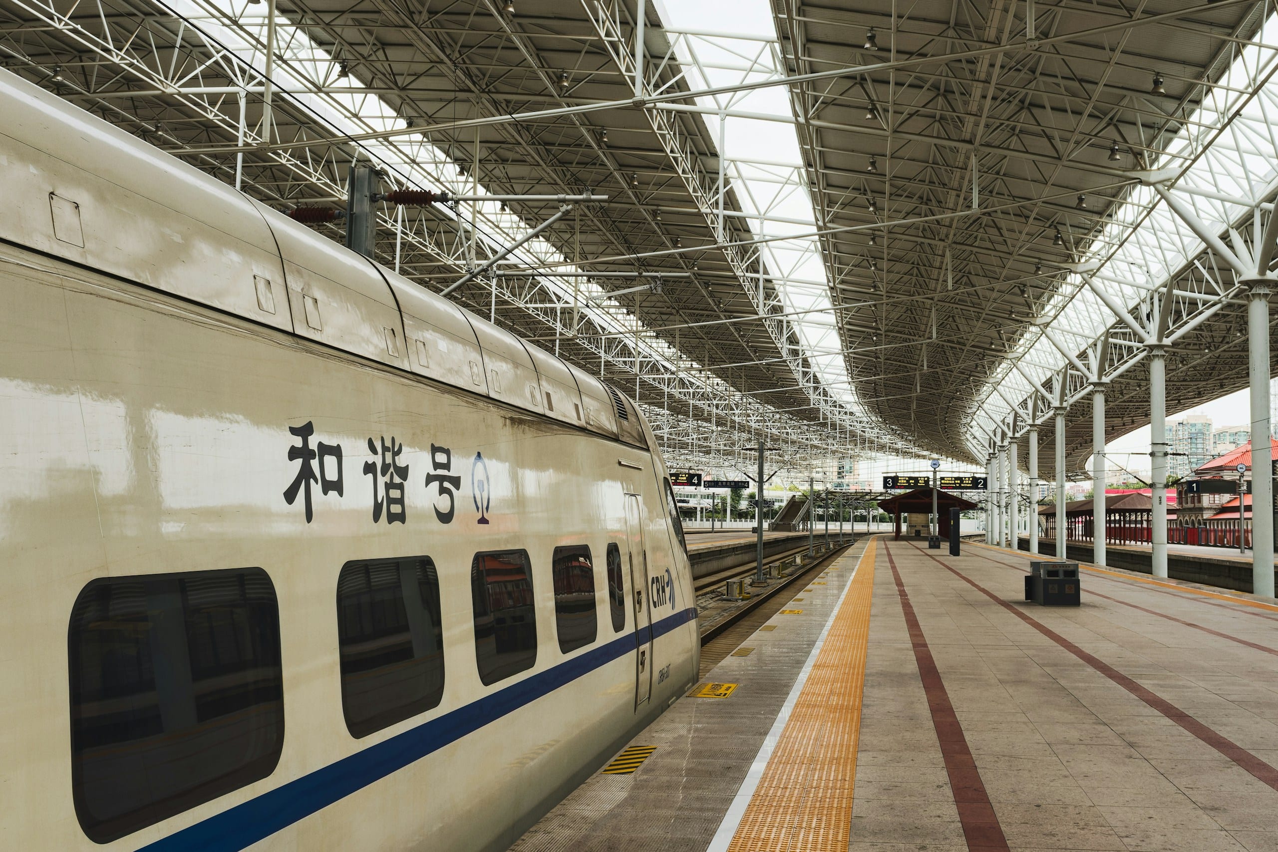A white high-speed train waiting at a modern station platform in China