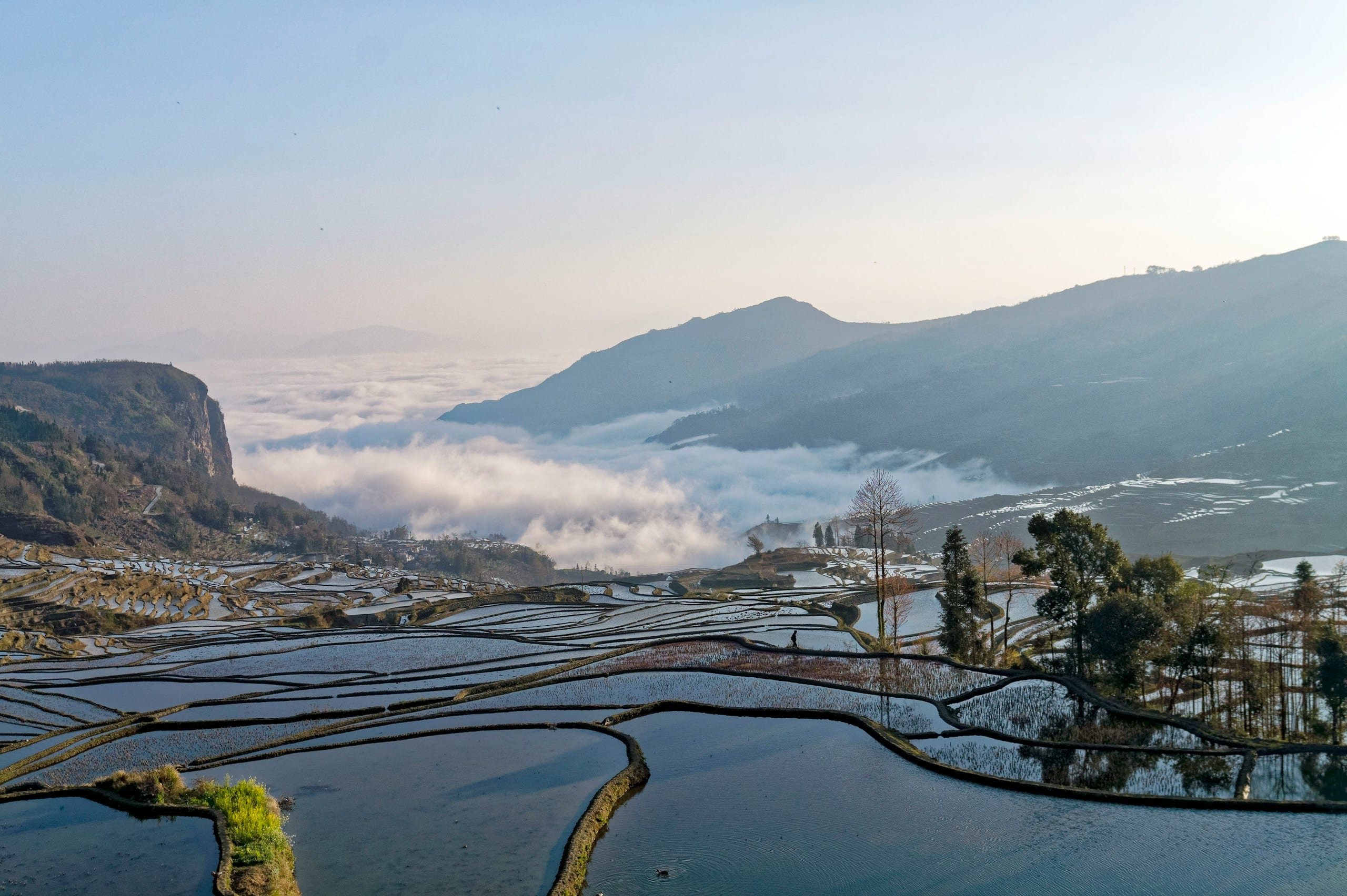Flooded rice terraces cascading down misty mountains in Yunnan, China
