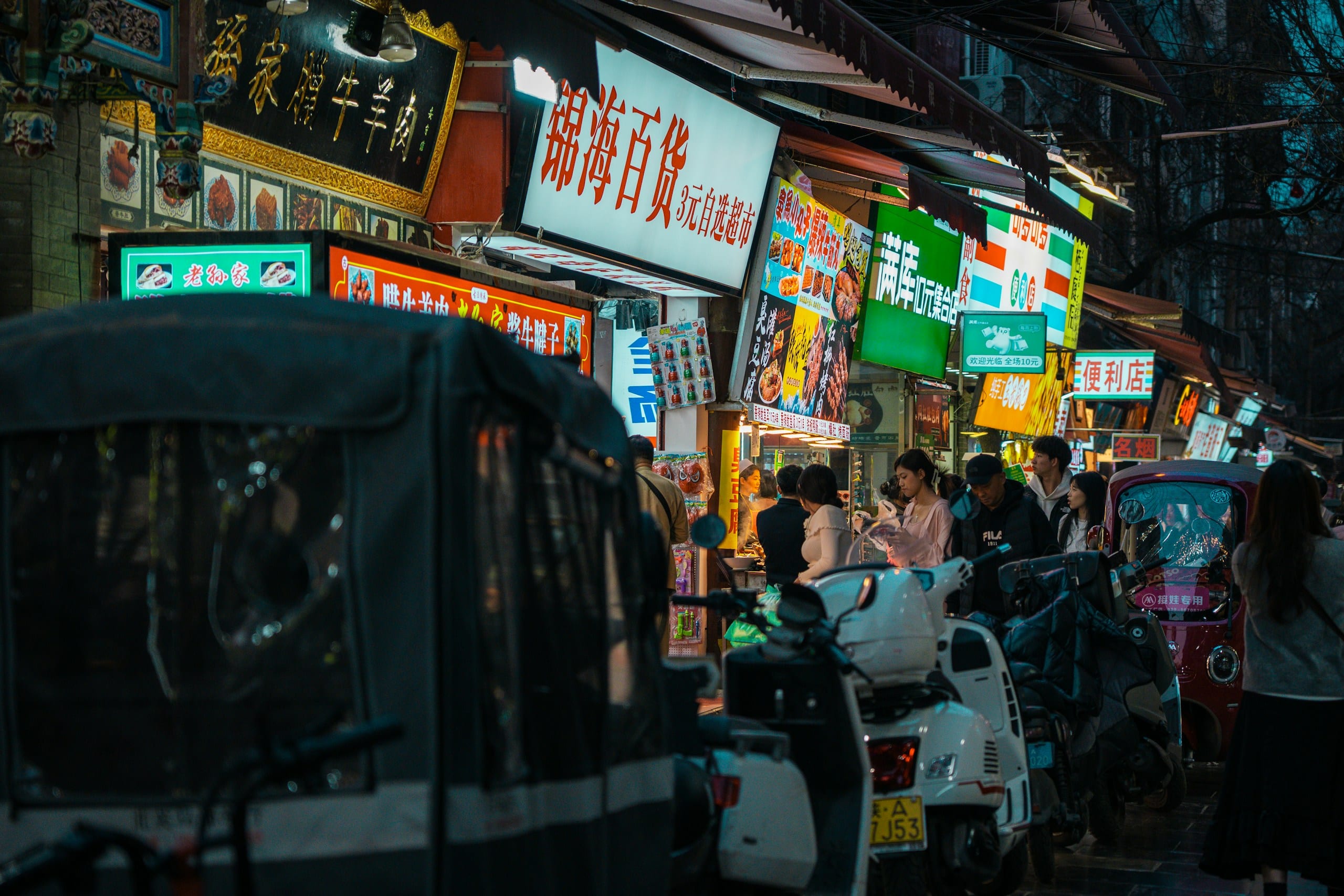 Crowded night street in Xi'an lined with lit food stalls and hanging skewers