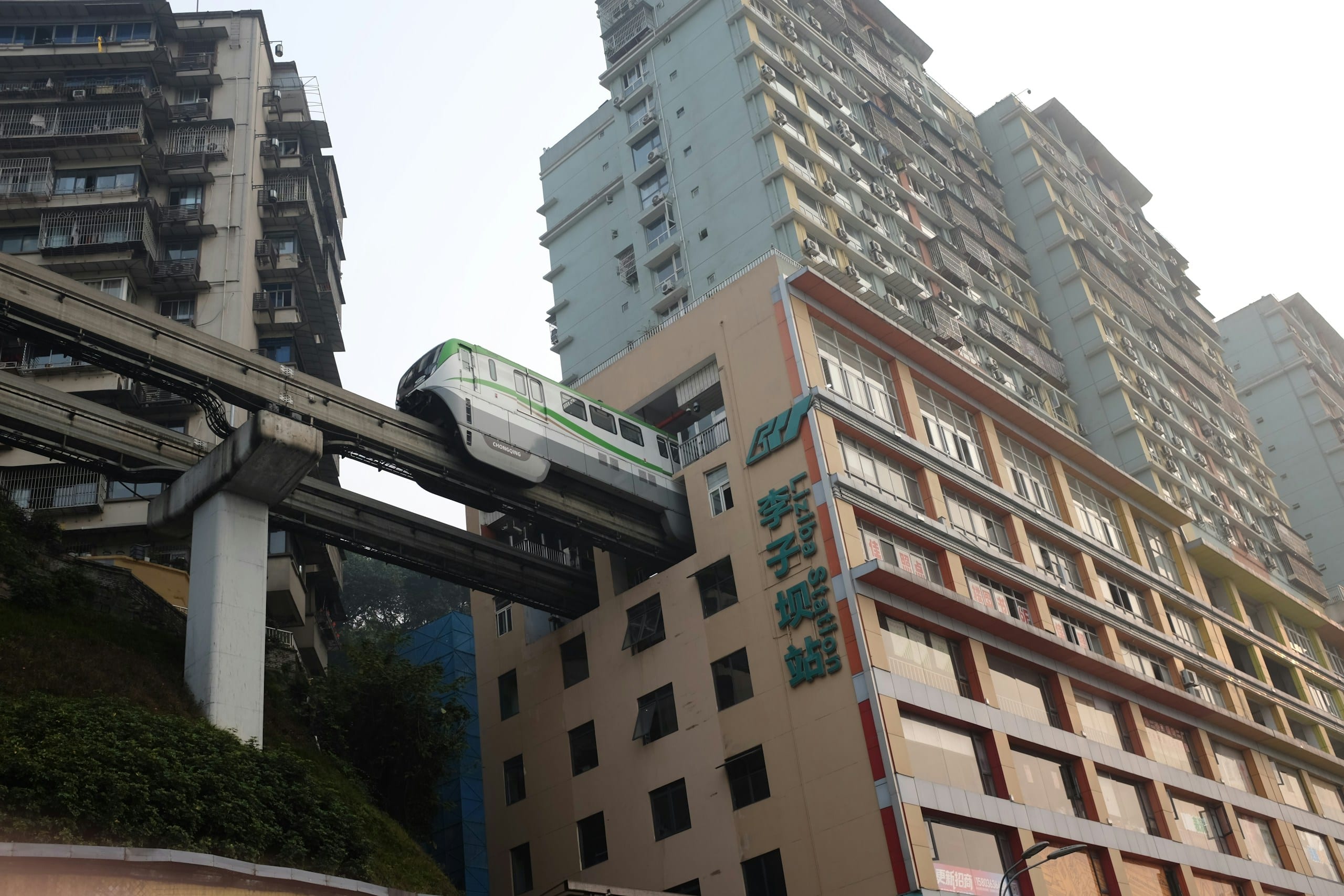 A Chongqing monorail train emerging from the middle floors of a high-rise residential building at Liziba station