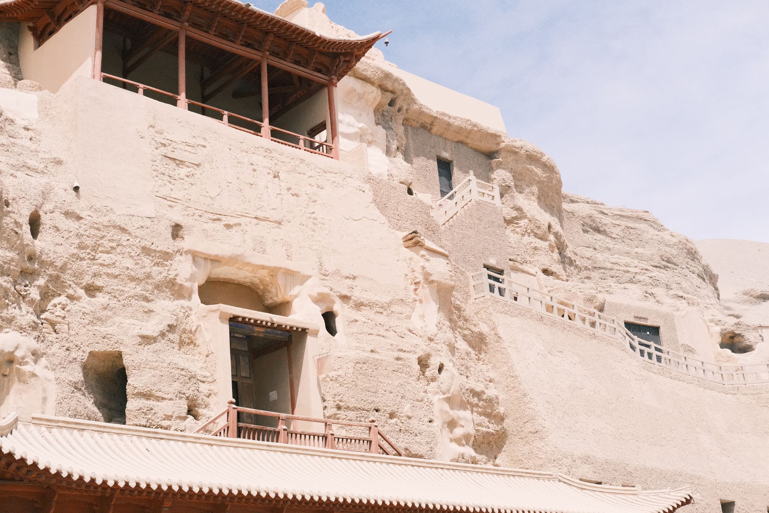 Sandstone cliff face at the Mogao Caves near Dunhuang with cave entrances and walkways built into the rock
