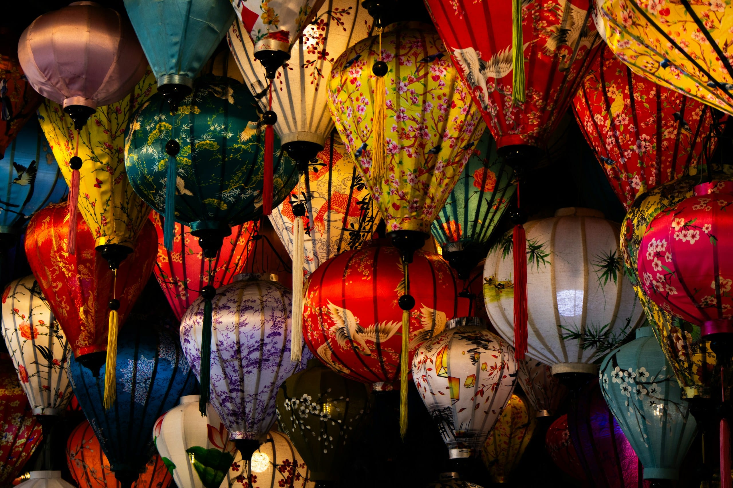 Rows of handmade paper lanterns in red, yellow, and blue hanging at Hoi An night market