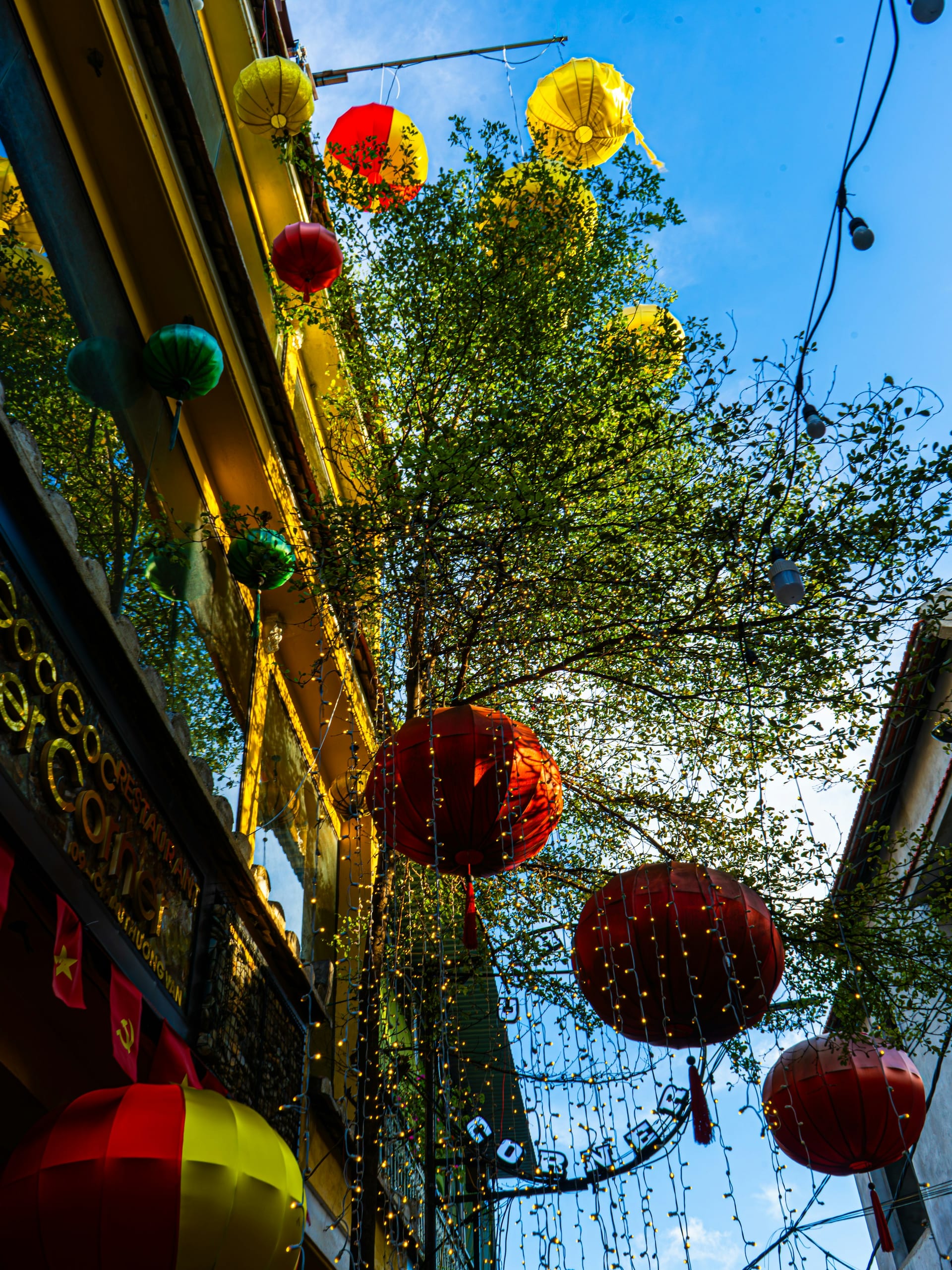 Red and yellow silk lanterns strung above a narrow street in Hoi An's old town at dusk