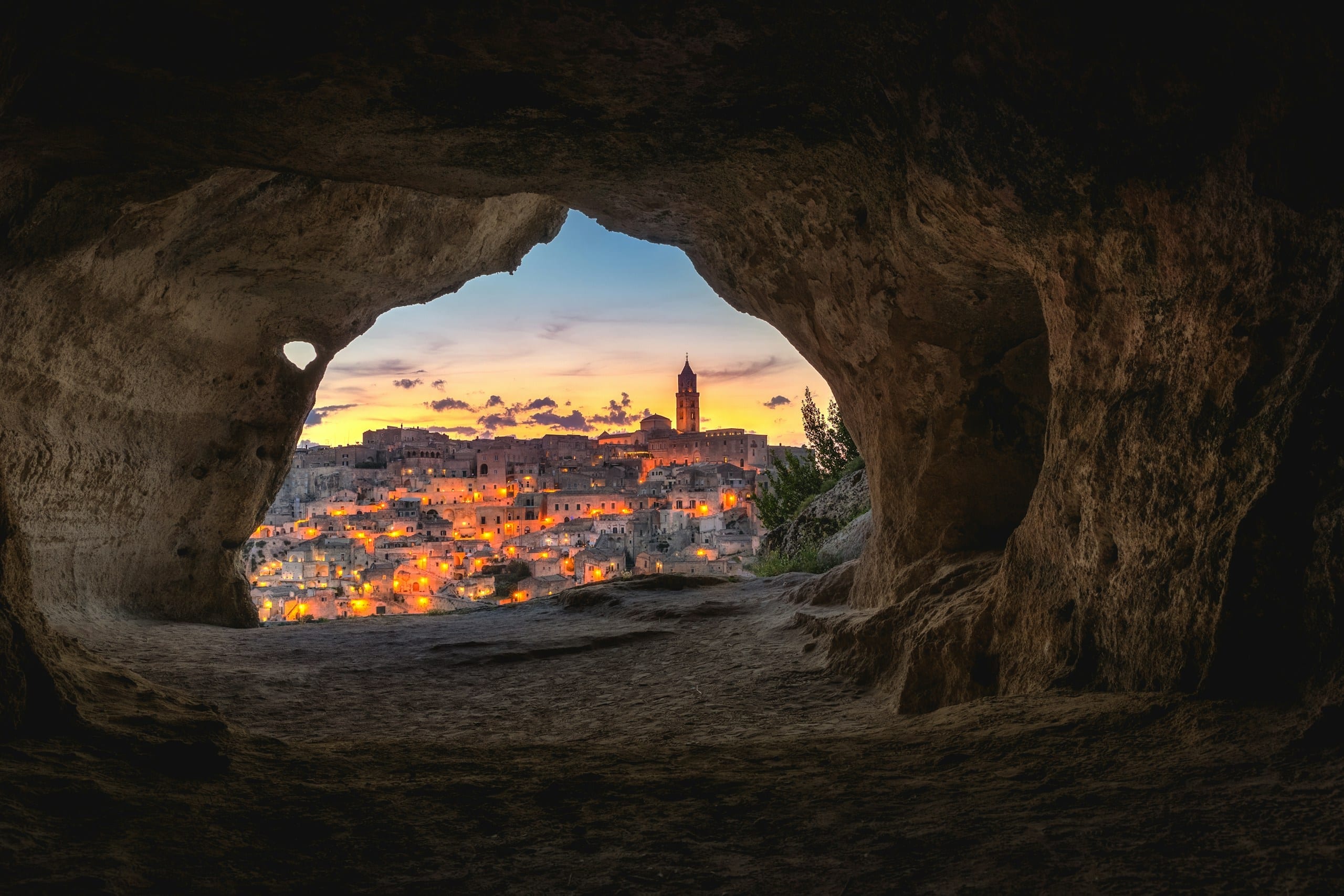 The stacked stone houses and cave dwellings of Matera's Sassi districts glowing at blue hour above the Gravina canyon