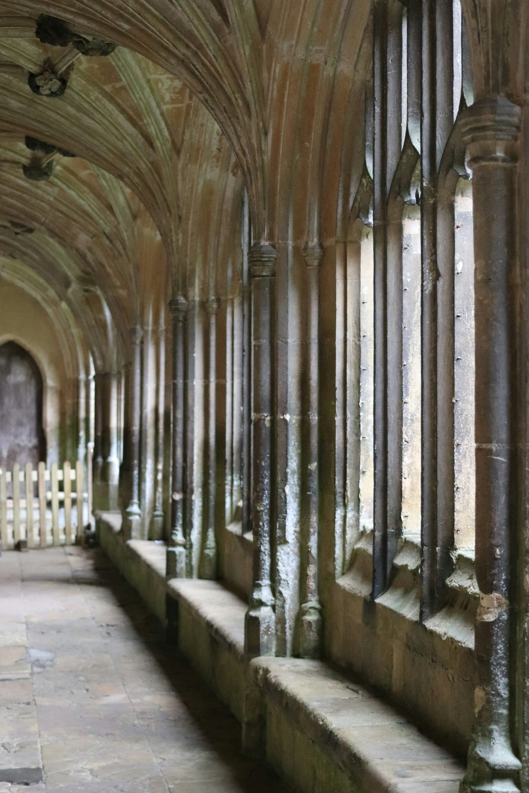 A quiet stone monastery cloister with arched walkways around a simple courtyard in soft morning light