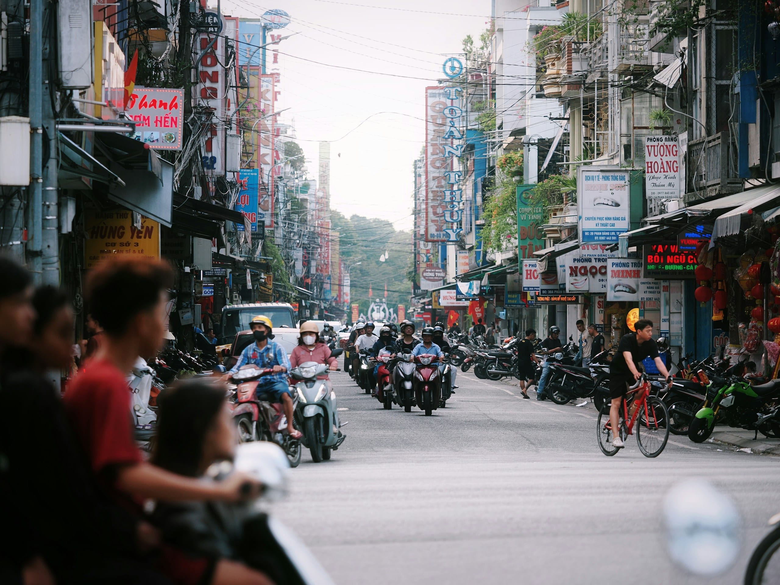 A dense flow of motorbikes and scooters on a Ho Chi Minh City street lined with mid-rise buildings