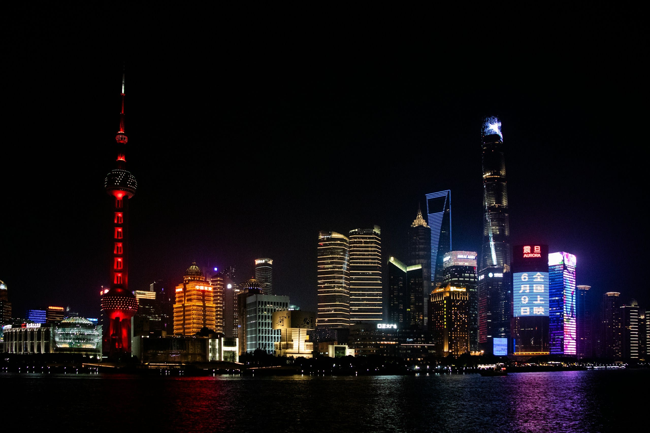 The Shanghai Pudong skyline at night seen from the Bund with the Oriental Pearl Tower lit up across the Huangpu River