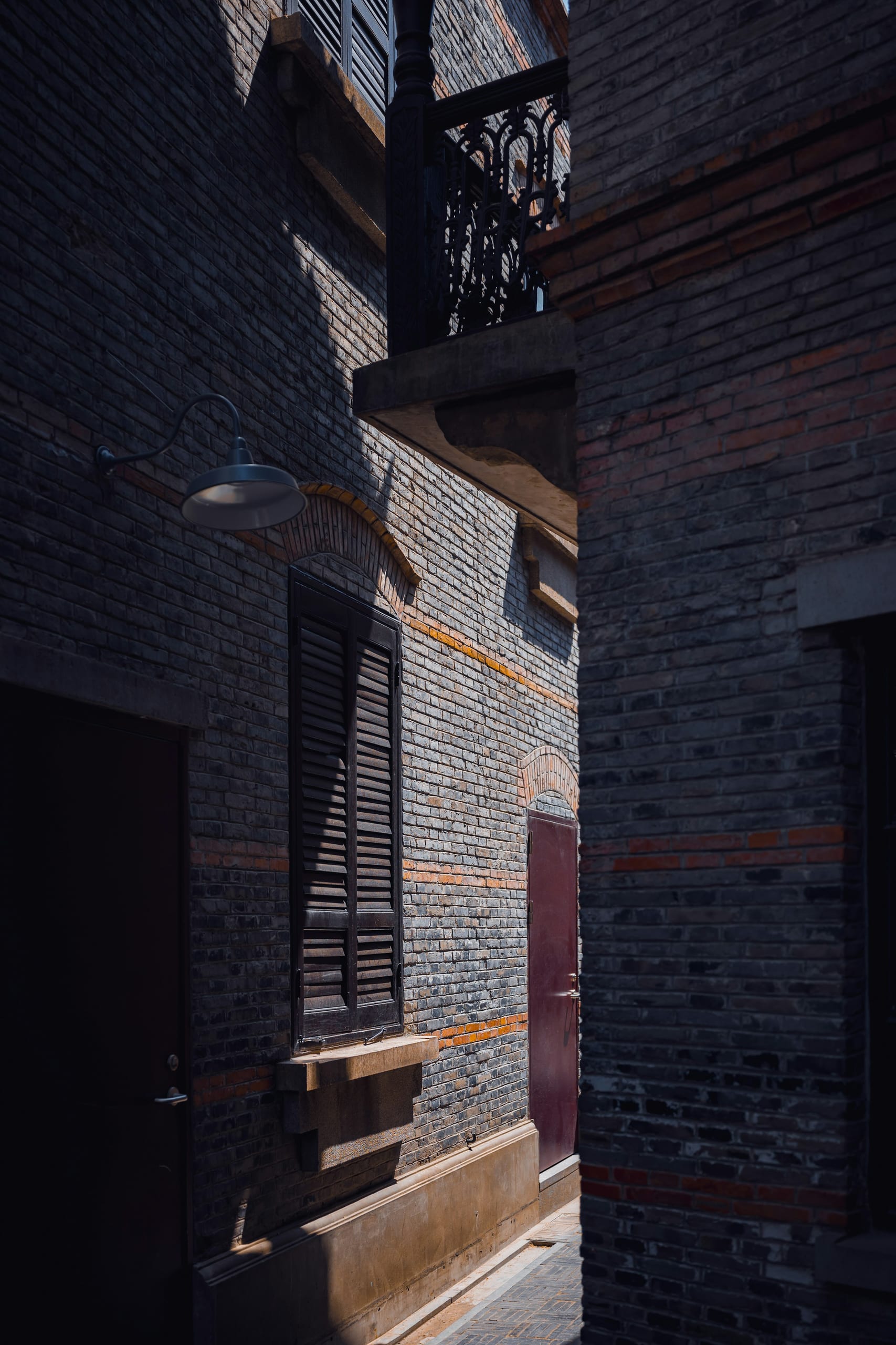 A narrow Shanghai lane between stone and brick buildings with laundry lines and a red door