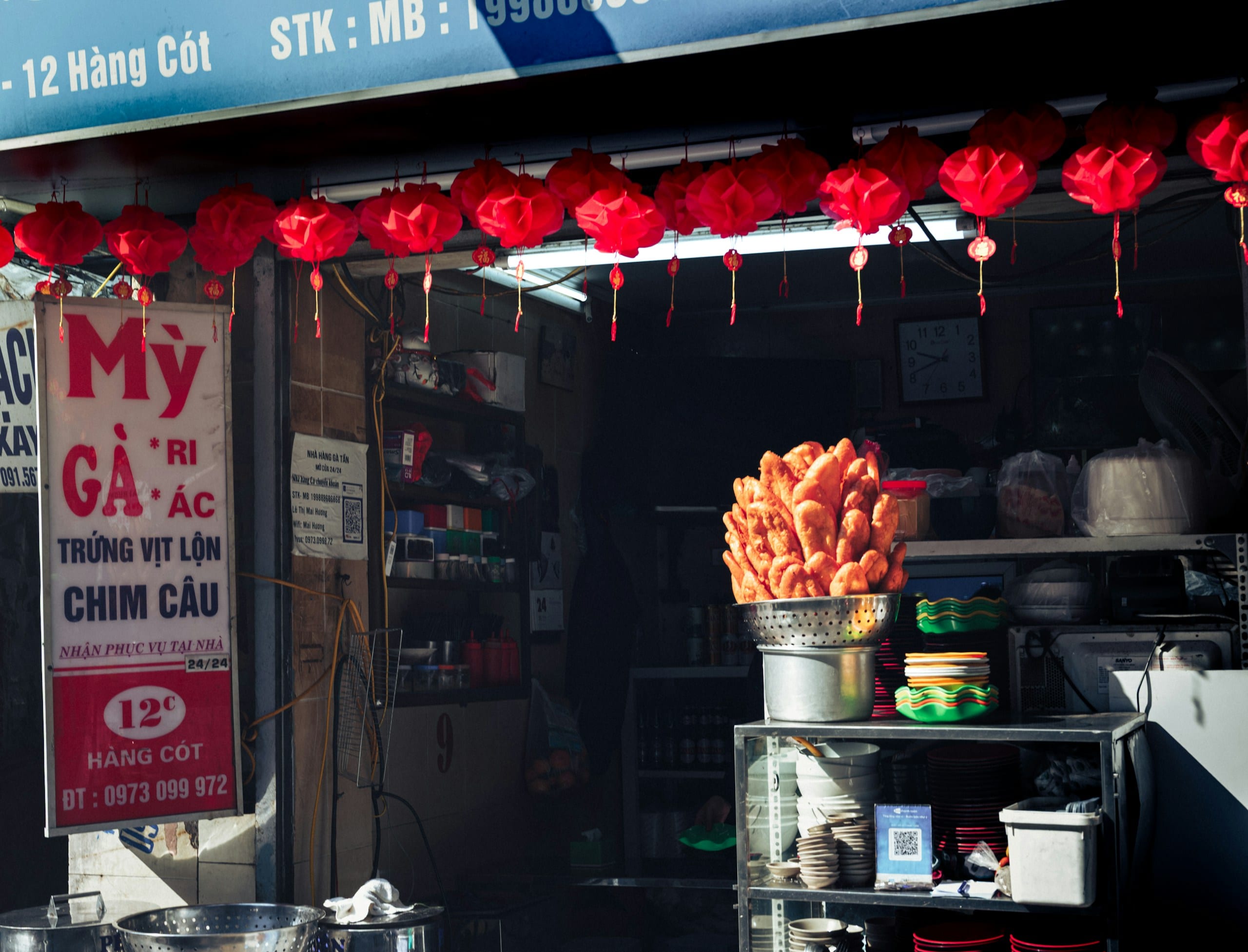 A street food stall in Hanoi lit by red lanterns with fried snacks on display
